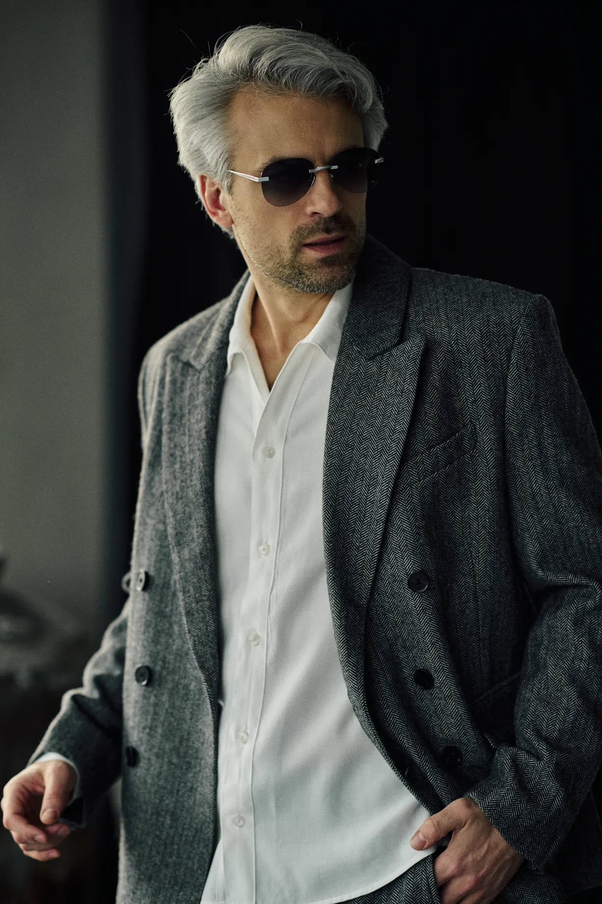 Man in a grey herringbone double-breasted jacket wearing PTERON Charcoal silver aviator sunglasses