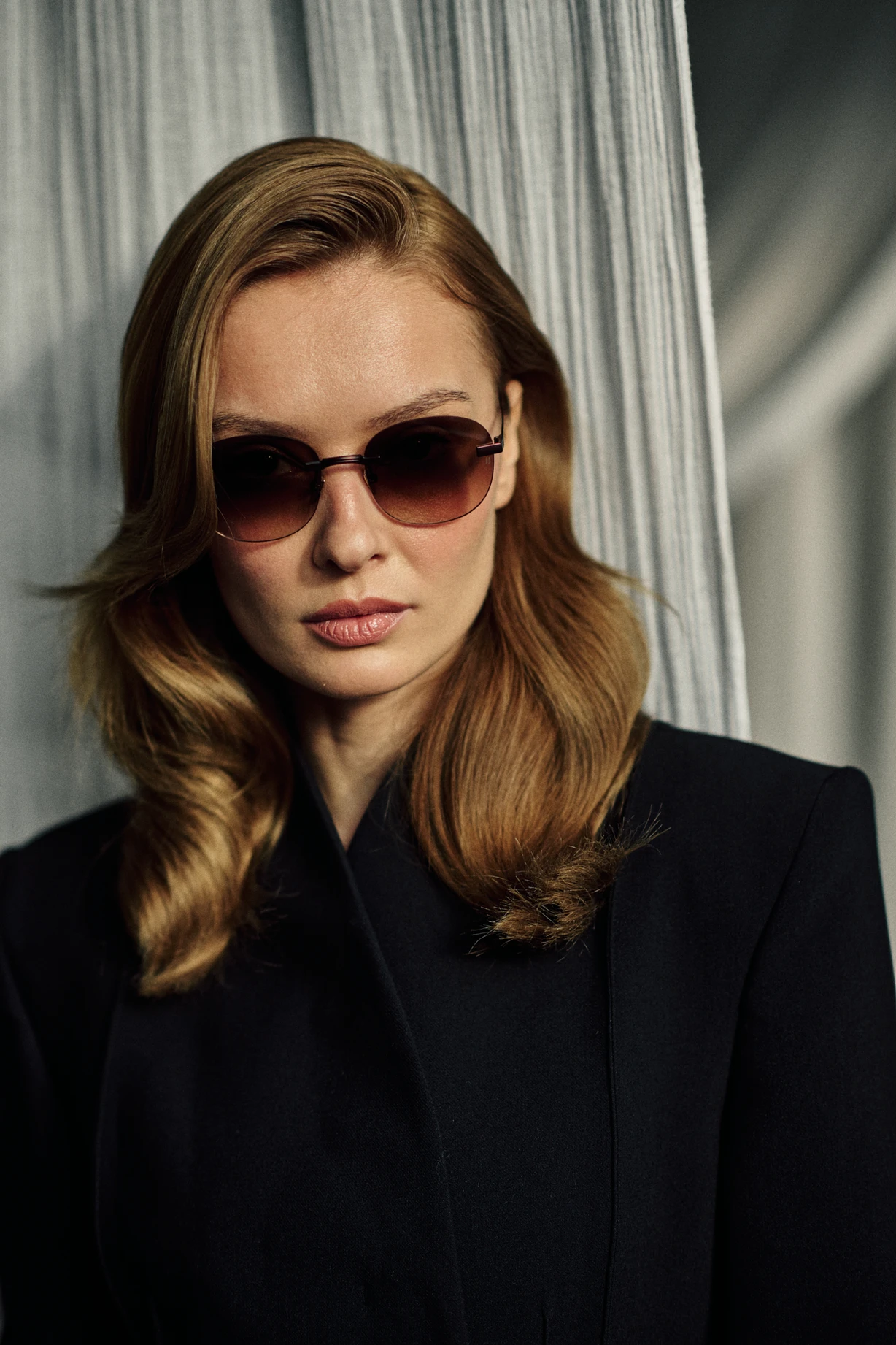 Woman in a black jacket wearing KAIROS Amber brown titanium sunglasses with brown gradient lenses