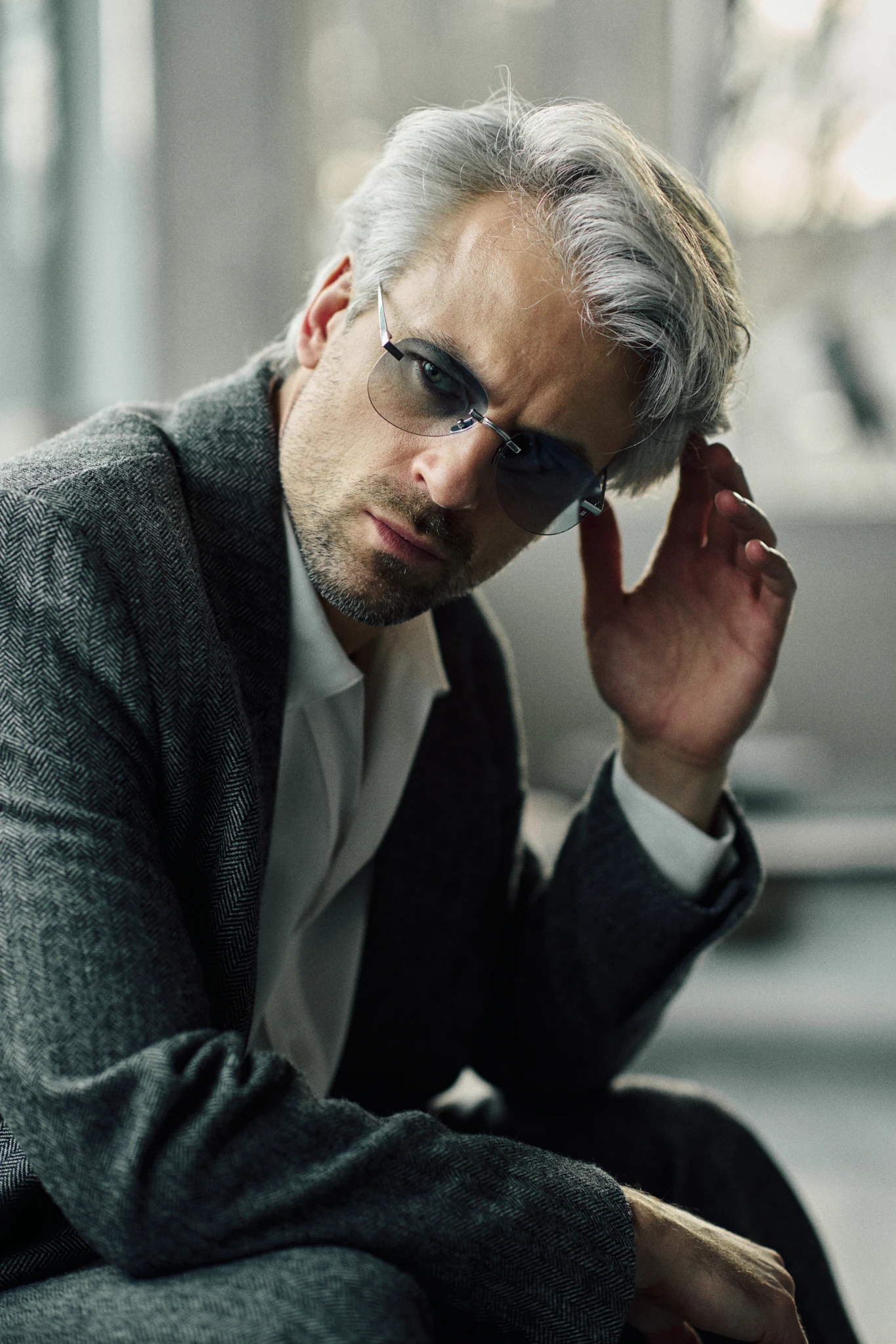 Man in a herringbone jacket wearing PTERON Azure silver aviator sunglasses with blue gradient lenses